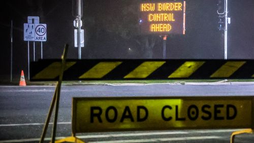 Road signs are displayed near a NSW border police checkpoint.