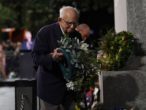 Wally Smith moves a floral tribute during the Anzac Day dawn service at Martin Place in Sydney. (9NEWS)