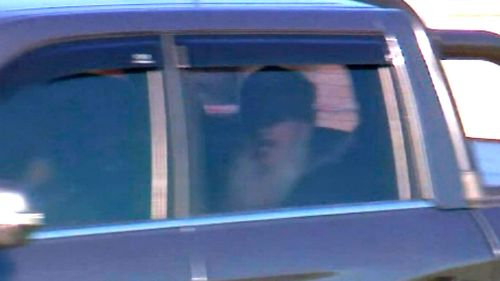Benbrika being driven out of Barwon prison in the back seat of a dark-coloured ute.