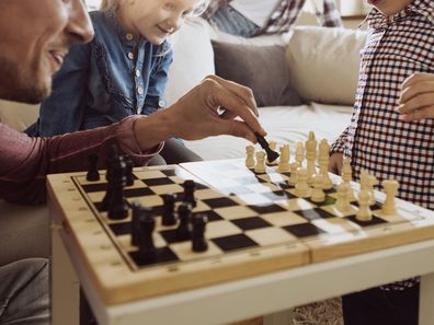 Young family enjoying time at home playing chess together