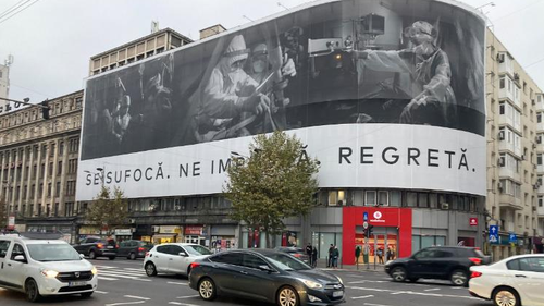 A banner in Bucharest shows medics working on COVID-19 patients with this message: "They're suffocating. They're begging us. They're regretting."