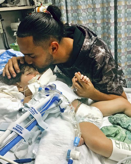 Ali Hassan kissing his dying 2-year-old son Abdullah in a Sacramento hospital. The boy's Yemeni mother, blocked by the Trump administration's travel ban, has won her fight for a waiver that would allow her to travel to California to see her son. 