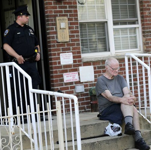 James Shields Sr waits outside a Queens apartment block as police process the crime scene where his son murdered three people. (AP)