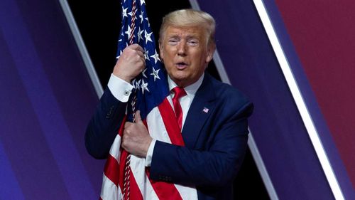 Donald Trump abraza una bandera en el CPAC del año pasado.