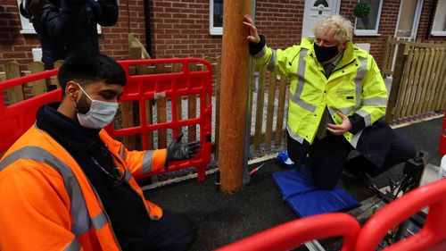 Prime Minister Boris Johnson meets apprentice Zuber Shaikh (L), who is demonstrating groundwork laying during a visit to the Openreach L and D Training Centre in In Bolton on December 18, 2020 in Manchester, England.