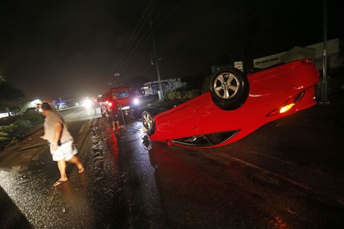 People tend to a car that flipped over on Cape Coral Parkway during Hurricane Irma. (AP)