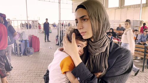 Australian woman Sara El-Masri with one of her children at the Rafah border crossing.