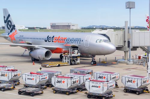 A Jetstar plane is loaded with cargo at Brisbane Airport
