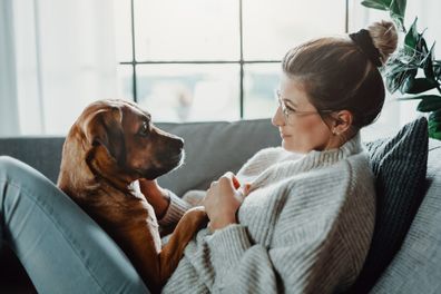 Woman and dog sitting on couch.