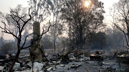 The ruins of a house smoulders on Old Bar road Near Taree, NSW