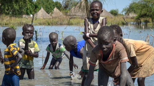 Children wash themselves in muddy floodwaters in the village of Wang Chot, in South Sudan.