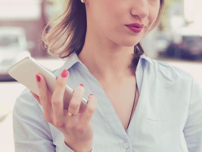 Woman holding phone, looking unimpressed