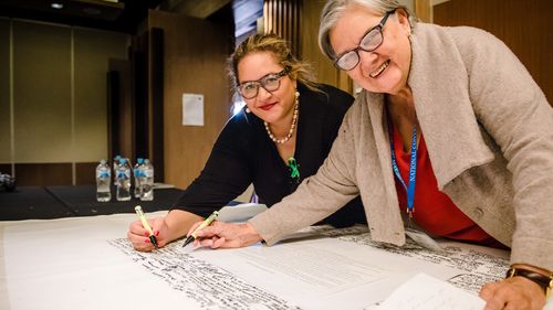 Uluru Dialogue co-chairs Professor Megan Davis and Pat Anderson sign the Uluru Statement from the Heart.