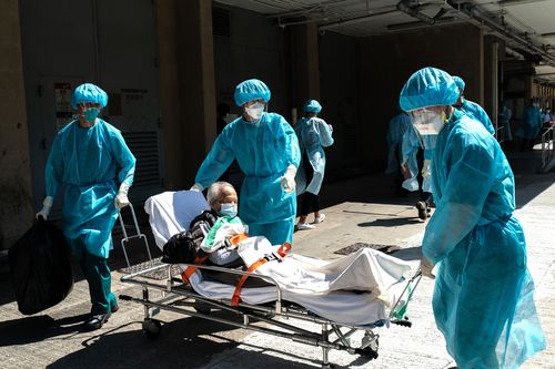 A elderly man in Hong Kong is carried on a stretcher by paramedics on to a minibus as residents are evacuated from a nursing home to a quarantine centre after multiple infections of the Covid-19. 