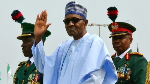 Nigerian President Muhammadu Buhari waves to the crowd during the 58th anniversary celebrations of Nigerian independence, in Abuja, Nigeria. Nigeria's president on Sunday Dec. 2, 2018, took the extraordinary step of denying rumors that he died and was replaced by a body double, telling the country that he is alive and well.