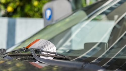 Bilhete de estacionamento exibido no para-brisa de um carro.