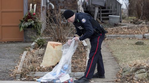 A police officer investigates outside a house on Mallory Crescent in Toronto, where Bruce McArthur did landscape work,