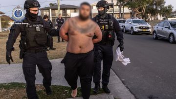 A﻿ man has been charged for posing in a photo with a toddler holding guns the day before a man was executed in a shooting gangland murder.