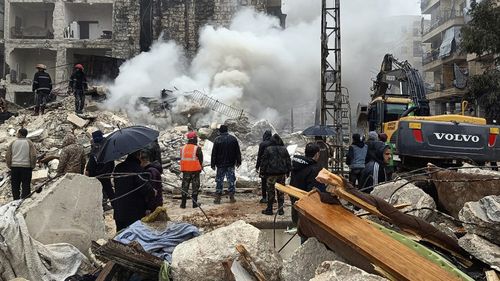 In this photo released by the Syrian official news agency SANA, civil defense workers and security forces search through the wreckage of collapsed buildings in Aleppo, Syria, Monday, Feb. 6, 2023. 