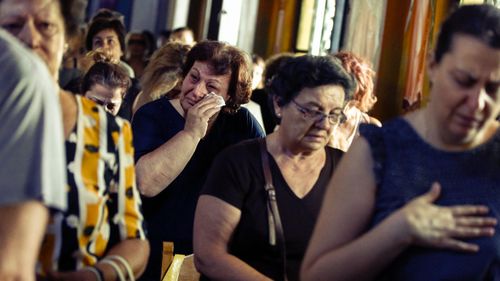 Greek Orthodox faithful attend a memorial service for the victims of a forest fire, at a church in Mati. (Image: AP)