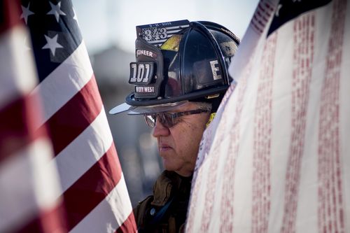 Retired fire engineer Bill Marshall wears his old firefighting gear and carries a flag with the names of all 3,000 people killed in the September 11 attacks as he walks through the Healing Fields at Tempe Beach Park in Tempe, Arizona, USA