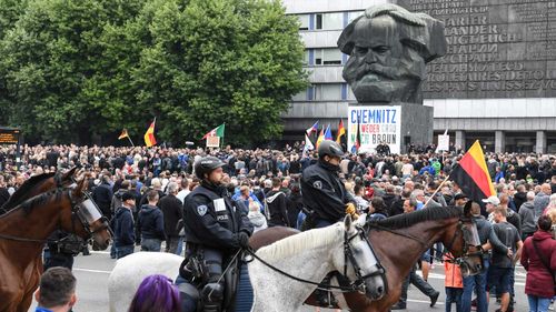 Mounted police surround a protest beneath a statue of Karl Marx in Chemnitz.