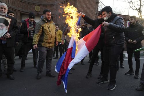 Iranian demonstrators set fire to French flags during their gathering to protest against the publication of offensive caricatures of the Iranian Supreme Leader Ayatollah Ali Khamenei in the French satirical magazine Charlie Hebdo, in front of the French Embassy in Tehran, Iran, Sunday, Jan. 8, 2023. 