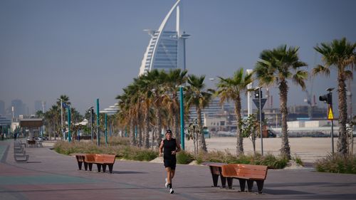 Un uomo fa jogging lungo una spiaggia con l'hotel di lusso Burj Al Arab sullo sfondo a Dubai, Emirati Arabi Uniti, domenica 1 marzo 2026. 