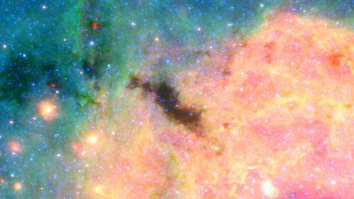 This view of the center of our galactic metropolis was captured by the Spitzer Space Telescope, offering an infrared view of the frenzied scene at the center of our Milky Way and revealing what lies behind the dust. "The Brick" is the dark blob at the center of the image, and the more advanced James Webb Space Telescope is offering researchers a closer look.