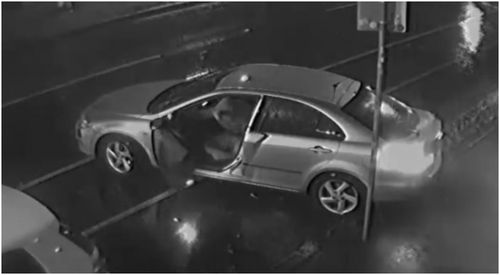 The passenger can be seen getting out of the car and running inside while the driver casually parks and waits for his associate to return. 