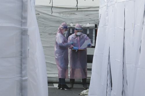 Medical staff wearing protective suits check documents as they wait for people with suspected symptoms of the new coronavirus, at a testing facility in Seoul, South Korea. Picture: Ahn Young-joon