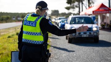 A Western Australia police officer inspects cars at a coronavirus border check point north of Perth, in June.