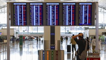 A passenger looks at an information display which shows almost all of the flights have been canceled due to the super typhoon Saola, at Hong Kong International Airport, in Hong Kong, on Friday, Sept. 1, 2023.  