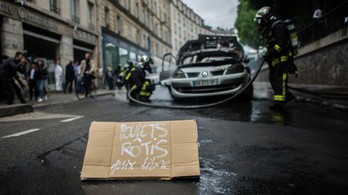 Protesters left a sign that read "free roast chickens" near the burned car. (AFP)
