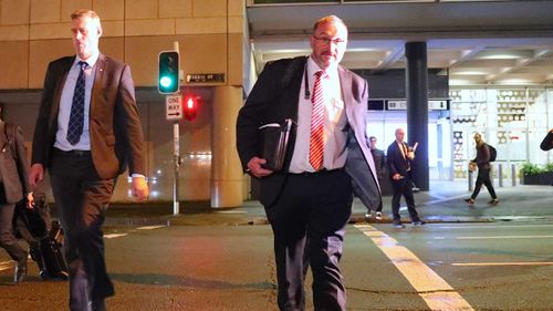 John Lyons (second right), Executive Editor of ABC News, watches as two Australian Federal Police officers cross the road outside the ABC building.