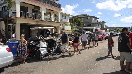 People walk past the home where a New Year's Eve fireworks explosion killed and injured multiple people in Honolulu, Hawaii.