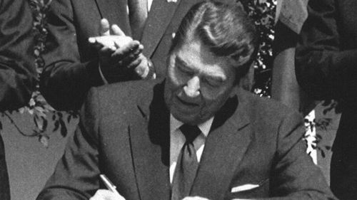 President Ronald Reagan signs legislation implementing the U.S.-Canada free trade agreement during a ceremony at the White House