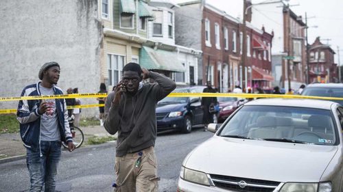 Onlookers gather as a shooting is investigated, Wednesday, Aug. 14, 2019, in Philadelphia.