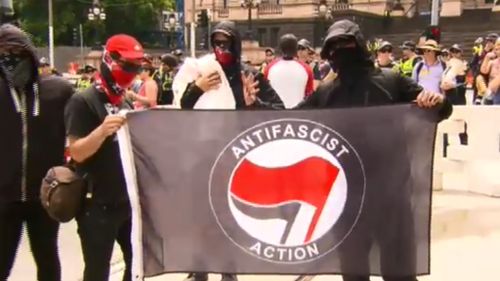 Masked protesters carry  "Anti-fascist Action" sign. (9NEWS)