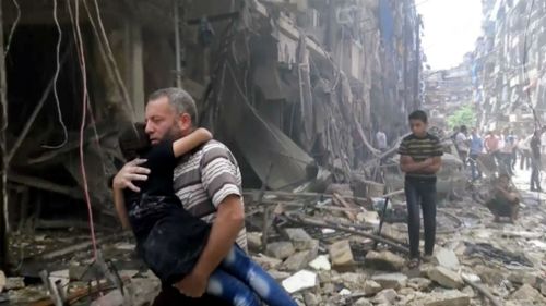 A man carries a child after airstrikes hit the Syrian city of Aleppo. (AAP)
