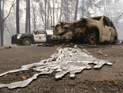 A California Highway Patrol vehicle passes a destroyed vehicle.