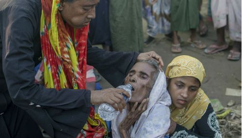 Rohingya Muslim woman Mustafa Khatoon is given water by a passerby as her daughter Hazra Begum waits for help to take her to a doctor near Mushani refugee camp. (AP)