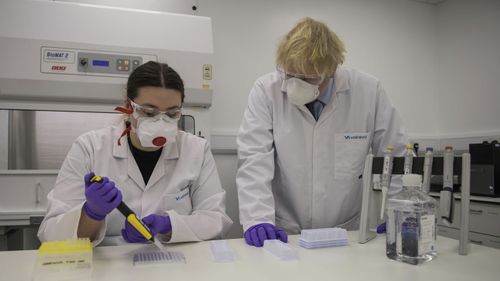Britain's Prime Minister Boris Johnson with quality control technician Kerri Symington, visits the French biotechnology laboratory Valneva in Livingston, Scotland, Thursday Jan. 28, 2021, where they will be producing a COVID-19 vaccine on a large scale, during a visit to Scotland. 