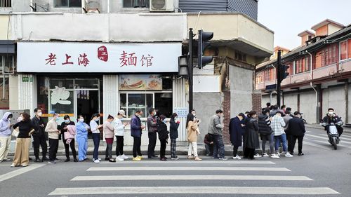 Residents line up near a noodle shop along a street for the COVID-19 test at a hospital in Shanghai. 
