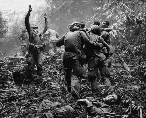 As US troopers aid wounded comrades, the first sergeant of A Company, 101st Airborne Division, guides a helicopter through the jungle foliage to pick up casualties suffered during a five-day patrol near Hue, April 1968.