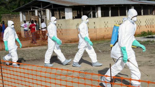 Liberian health workers in protective gear on the way to bury a woman who died of the Ebola virus. (AP)