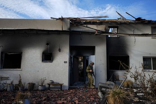 An Israeli soldier inspects a house damaged by Hamas militants in Kibbutz Be'eri, Israel, Tuesday, Oct. 17, 2023.