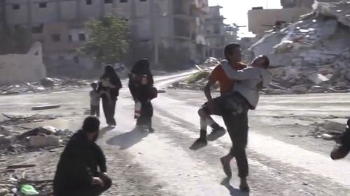 Frame grab from video shows Syrian civilians running on a damaged street as they flee areas that still controlled by Islamic State militants in Raqqa. (Mezopotamya Agency, via AP)