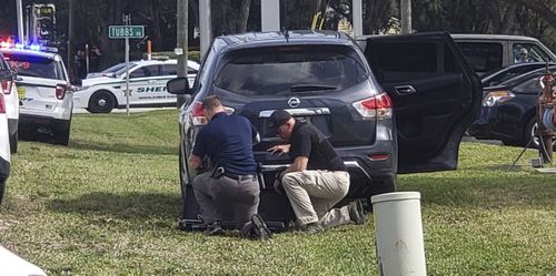 Law enforcement officials take cover outside a SunTrust Bank branch