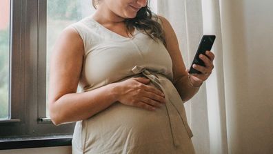 Pregnant woman reading on her mobile phone.